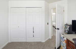Carpeted bedroom featuring a closet and baseboards