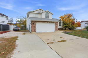 Traditional-style home with driveway, a shingled roof, brick siding, and an attached garage