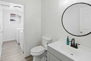 Bathroom with washer and dryer, light wood-type flooring, and vanity
