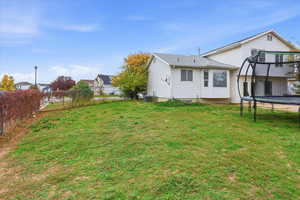 Rear view of property featuring a trampoline and roof with shingles