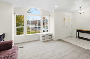 Entrance foyer with light carpet, a chandelier, light tile patterned flooring, and recessed lighting