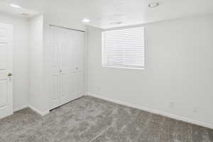 Unfurnished bedroom featuring light colored carpet, a closet, recessed lighting, and a textured ceiling