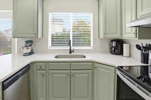 Kitchen with green cabinetry, range with electric cooktop, dishwasher, tasteful backsplash, and under cabinet range hood