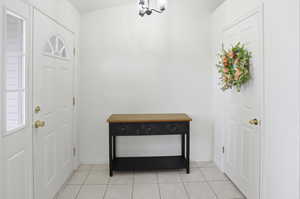 Foyer with light tile patterned floors and a chandelier