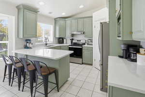 Kitchen with green cabinets, a peninsula, appliances with stainless steel finishes, backsplash, and recessed lighting