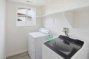 Laundry room with light wood-type flooring and washer and dryer
