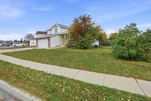 View of front of property with a front lawn, a garage, concrete driveway, and brick siding