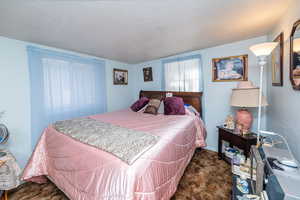 Carpeted bedroom featuring a textured ceiling and baseboards