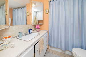 Bathroom with light tile patterned floors, vanity, and shower / tub combo with curtain