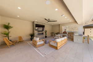 Living room with recessed lighting, ceiling fan, a stone fireplace, and light tile patterned floors