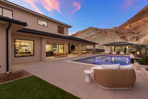 Outdoor pool with a patio area, a mountain view, an outbuilding, an outdoor hangout area, and a hot tub