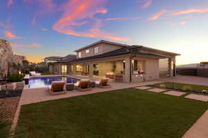Back of property at dusk featuring a patio, stucco siding, and an outdoor living space