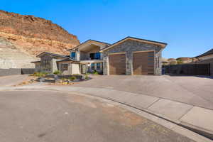 Modern home featuring a balcony, driveway, and stone siding