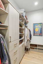Walk in closet with light wood finished floors
