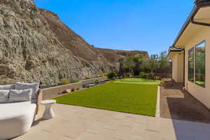 Fenced backyard with a patio, an area to practice putting, and a mountain view