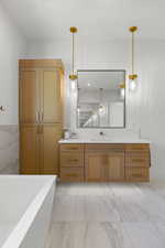 Bathroom featuring vanity, a freestanding bath, and light marble finish floors
