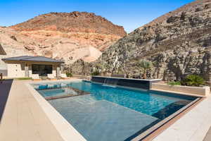 View of swimming pool featuring a patio area, a pool with connected hot tub, and a mountain view