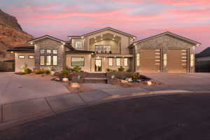 Contemporary house featuring a balcony, stone siding, driveway, and stucco siding