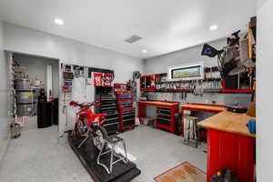 Miscellaneous room featuring secured water heater, recessed lighting, a workshop area, and dark speckled floor