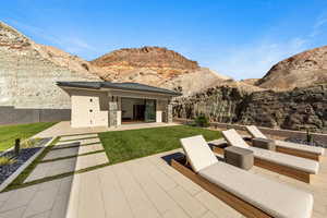 Rear view of property featuring a patio area, a mountain view, a yard, and stucco siding