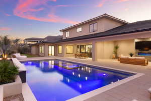 Back of house featuring outdoor lounge area, a patio, a pool with connected hot tub, and stucco siding