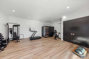 Workout room featuring light wood-type flooring, recessed lighting, and an AC wall unit