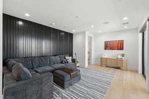 Living room featuring light wood-type flooring, recessed lighting, and an accent wall