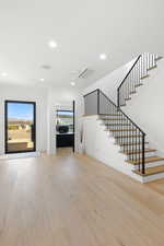 Unfurnished living room featuring recessed lighting, stairs, and light wood-type flooring