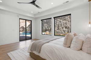 Bedroom with wood finished floors, recessed lighting, a ceiling fan, access to outside, and a tray ceiling