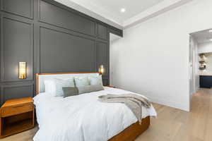 Bedroom with light wood-style floors, recessed lighting, and a decorative wall