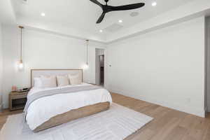 Bedroom featuring a raised ceiling, light wood-type flooring, a ceiling fan, and recessed lighting