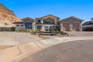 Contemporary home featuring stone siding, a balcony, concrete driveway, stucco siding, and a garage