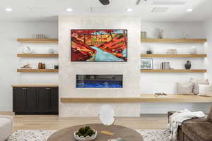 Living room with recessed lighting, a tiled fireplace, and light wood-style flooring