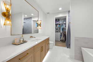 Bathroom with vanity, a spacious closet, recessed lighting, a bath, and light tile patterned floors