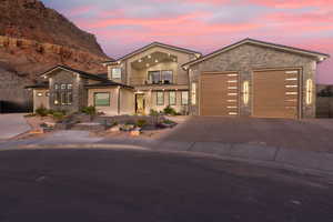 Contemporary home with a balcony, concrete driveway, an attached garage, stone siding, and stucco siding