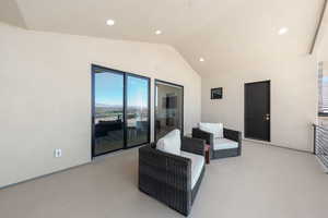 Living area with vaulted ceiling, light colored carpet, and recessed lighting