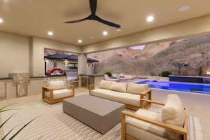 View of patio featuring an outdoor kitchen, ceiling fan, an outdoor hangout area, an outdoor pool, and a mountain view