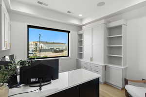 Office area with light wood finished floors, recessed lighting, and a raised ceiling
