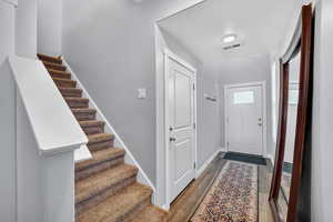 Foyer entrance with dark wood-style flooring, a textured ceiling, and stairway