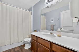 Bathroom featuring shower / tub combo with curtain, vanity, dark wood-style floors, and a textured ceiling