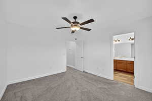 Unfurnished bedroom with light carpet, ceiling fan, and ensuite bathroom
