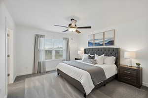 Carpeted bedroom with a ceiling fan and baseboards