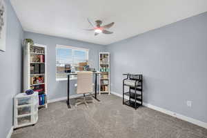 Carpeted home office with baseboards and a ceiling fan