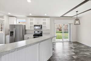 Kitchen with white cabinetry, stainless steel appliances, recessed lighting, light countertops, and hanging light fixtures