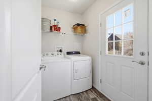 Washroom with dark wood finished floors and washer and clothes dryer