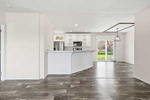 Kitchen featuring white cabinetry, recessed lighting, appliances with stainless steel finishes, dark wood-style flooring, and a breakfast bar area