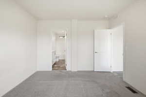 Unfurnished bedroom with carpet floors and ensuite bath