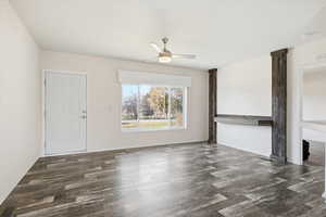Unfurnished living room featuring dark wood-style floors and a ceiling fan