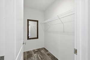 Walk in closet with dark wood-style flooring