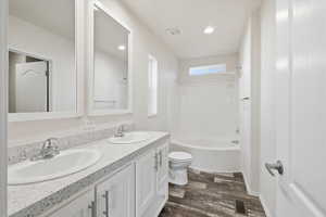 Full bathroom featuring double vanity, shower / tub combination, dark wood-style floors, and recessed lighting
